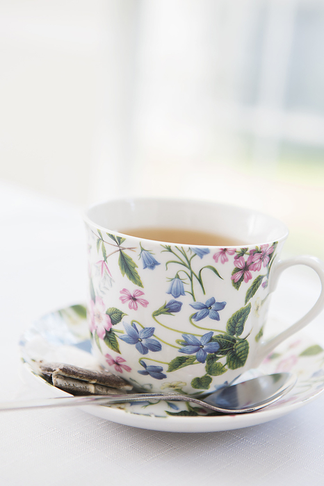 Cup of tea in pretty floral cup with saucer and used tea bag, studio shot, by Amy Whitt / Design Pics