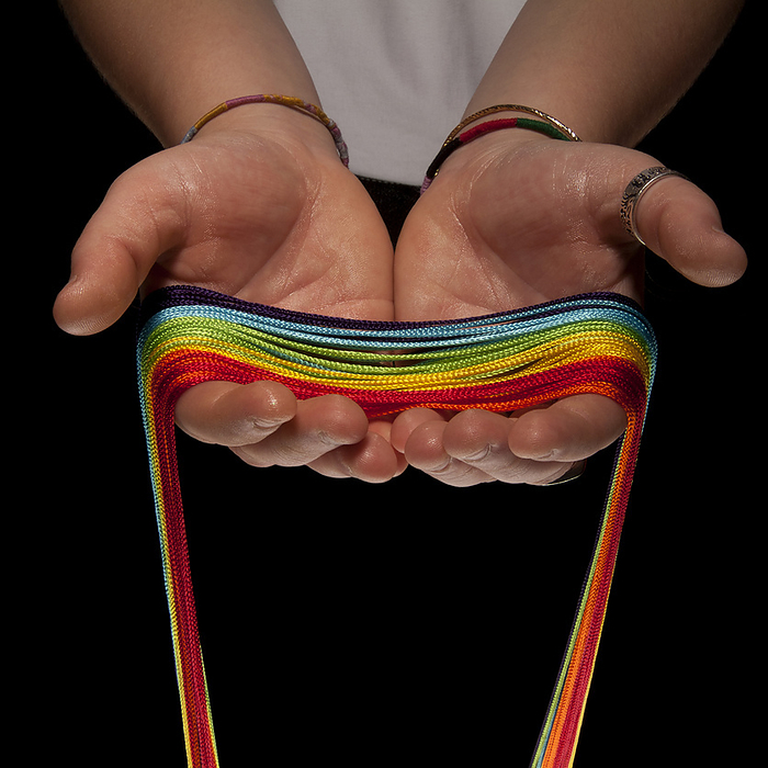 Close-up of Teenager's Hands holding Rainbow Colored Strings, Studio Shot, by Gary Rhijnsburger / Design Pics