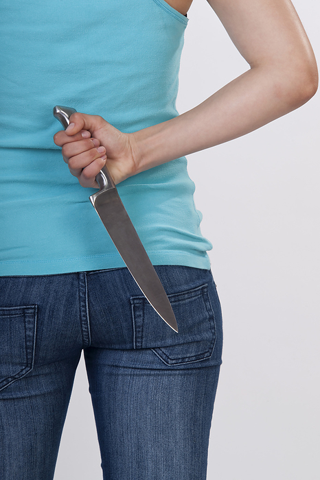 Woman Holding a Knife Behind Her Back, by Jens Lüebkemann / Design Pics