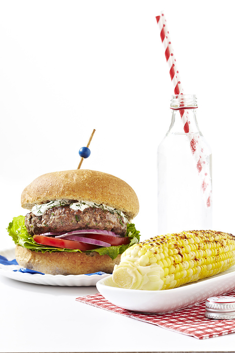 Greek style burger with spiced corn on the cob and bottle of soda with striped straws, studio shot on white background, by Jodi Pudge / Design Pics