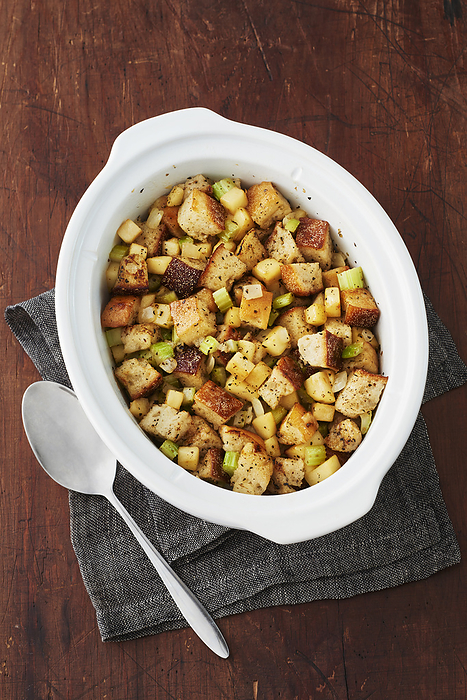 Serving dish of bread stuffing with spoon on a wooden background, by Jodi Pudge / Design Pics
