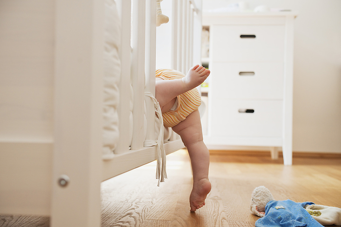 Baby Girl Climbing into Crib, by I. Jonsson / Design Pics