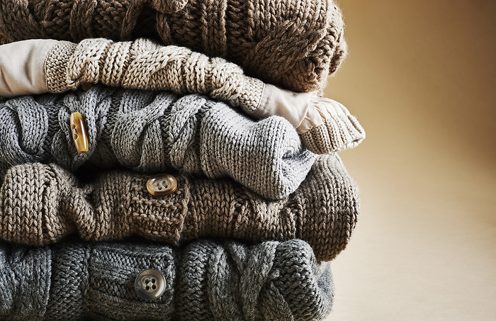 Close-up of stack of five cardigans, studio shot on brown background, by I. Jonsson / Design Pics