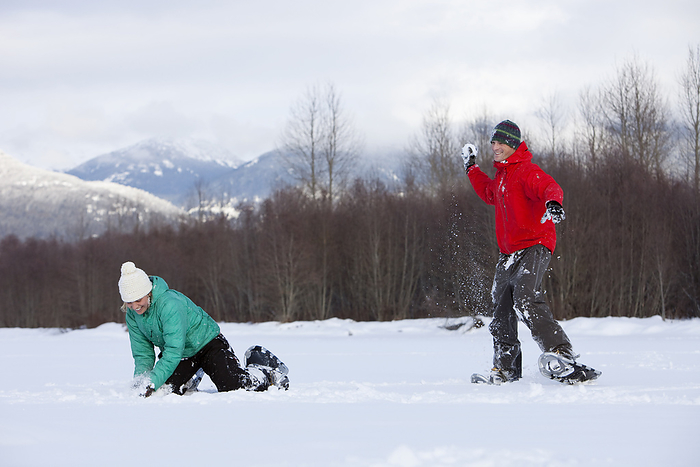 Couple Wearing Snowshoes having a Snowball Fight, Whistler, British Columbia, Canada, by Noel Hendrickson / Design Pics