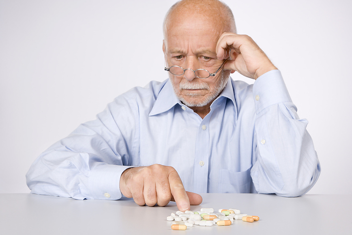 Man Looking at Pills, by Norbert Schäfer / Design Pics