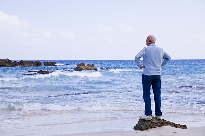 Man Standing on Rock Looking Out to Sea, by Norbert Schäfer / Design Pics
