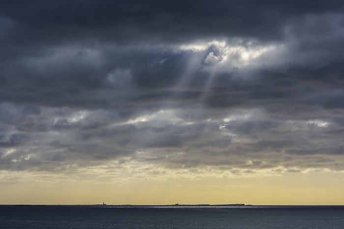 United Kingdom Sun shining through rain clouds over Farne Island in the North Sea at Bamburgh, England, Northumberland, by Raimund Linke   Design Pics