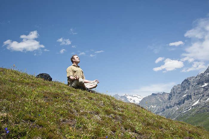 Man Sitting on Mountain Side, Meditating, Bernese Oberland, Switzerland, by Uwe Umstätter / Design Pics