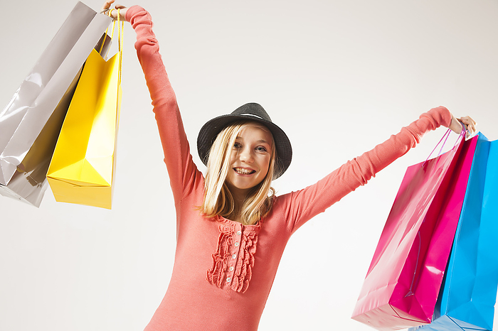 Low Angle View Portrait of Blond, Teenage Girl wearing Hat and holding Shopping Bags in Air, Studio Shot on White Background, by Uwe Umstätter / Design Pics