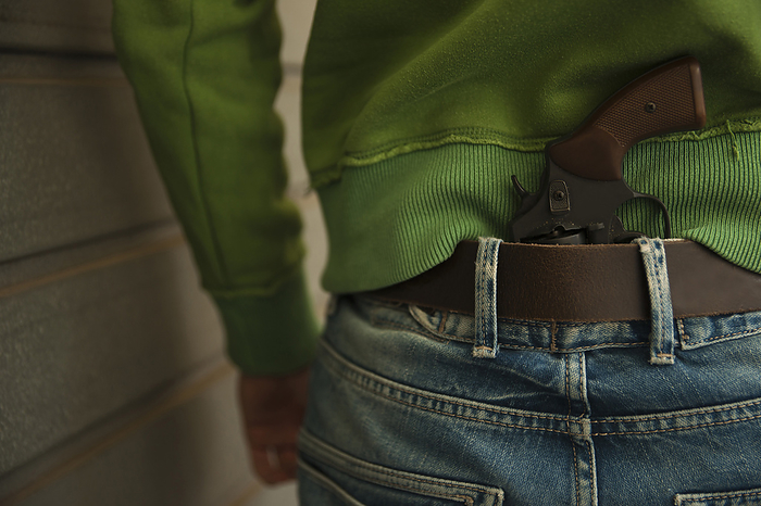 Close-up of Back of Young Man with Handgun Tucked into Waistband of Blue Jeans, Mannheim, Baden-Wurttemberg, Germany, by Uwe Umstätter / Design Pics