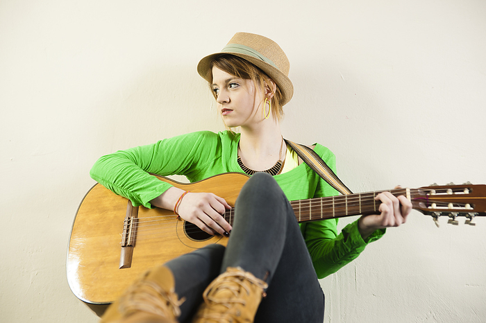 Portrait of Teenage Girl Wearing Hat and Playing Acoustic Guitar, Studio Shot on White Background, by Uwe Umstätter / Design Pics