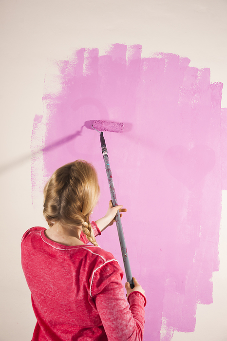 Studio Shot of Young Woman Painting Wall Pink, by Uwe Umstätter / Design Pics