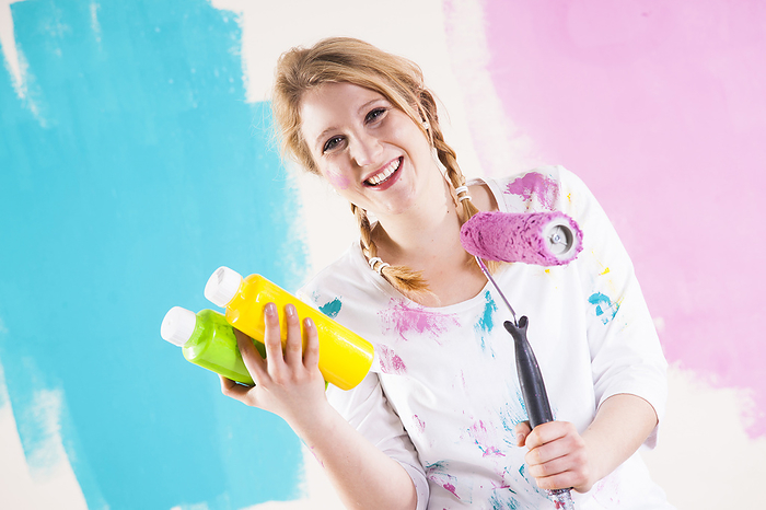 Studio Shot of Young Woman Holding Paint Roller, Deciding Between Paint Colours, by Uwe Umstätter / Design Pics