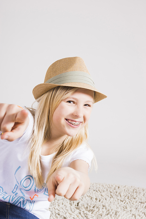 Portrait of Girl wearing Hat and Pointing at Camera in Studio, by Uwe Umstätter / Design Pics