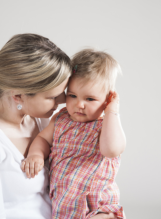 Portrait of Mother holding Crying Baby Girl, Studio Shot, by Uwe Umstätter / Design Pics