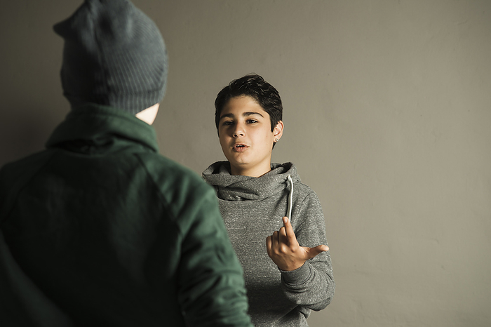 Teenage Boy Talking to another Boy, Studio Shot, by Uwe Umstätter / Design Pics