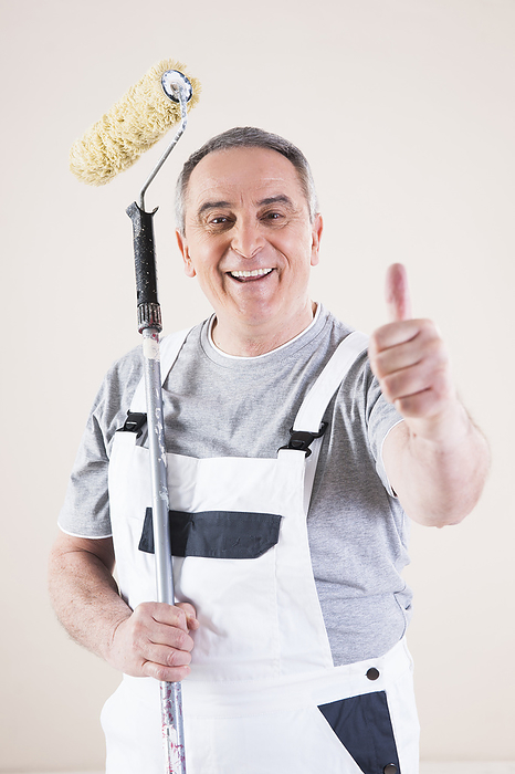 Portrait of Painter giving Thumbs Up and holding Paint Roller, Studio Shot, by Uwe Umstätter / Design Pics