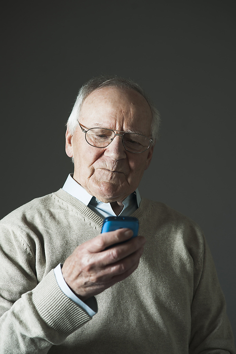Elderly Man using Cell Phone in Studio, by Uwe Umstätter / Design Pics