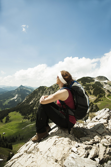 Mature woman sitting on cliff, hiking in mountains, Tannheim Valley, Austria, by Uwe Umstätter / Design Pics