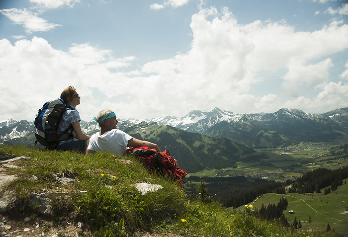 Backview of mature couple sitting on grass, hiking in mountains, Tannheim Valley, Austria, by Uwe Umstätter / Design Pics