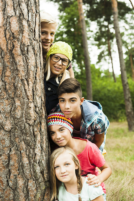 Portrait of group of children posing next to tree in park, Germany, by Uwe Umstätter / Design Pics