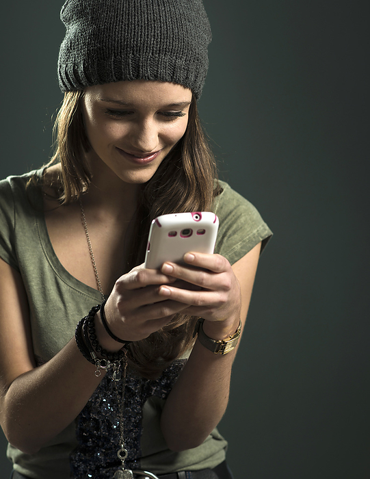 Portrait of Teenage Girl using Cell Phone, Studio Shot, by Uwe Umstätter / Design Pics