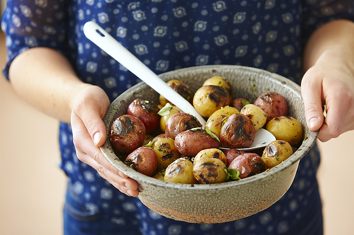 Close-up of Woman's Hands Holding Bowl of Grilled Red and White Baby Potatoes, by Yvonne Duivenvoorden / Design Pics