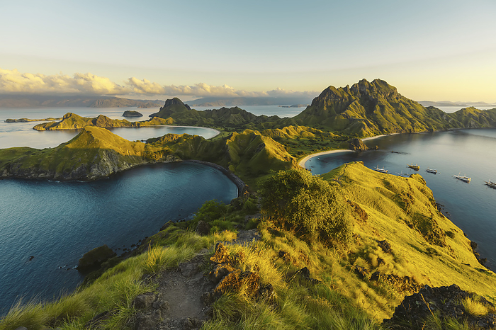 Boats moored in the bay at Padar Island in Komodo National Park in the Komodo Archipelago with sunlit grassy slopes at sunset; East Nusa Tenggara, Indonesia, by O'Neil Castro / Design Pics