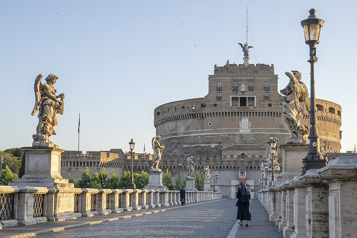 View of the Castel Sant'Angelo (Mausoleum of Hadrian) with a pedestrian and a Nun crossing the Ponte Sant'Angelo; Rome, Lazio, Italy, by Chris Caldicott / Design Pics