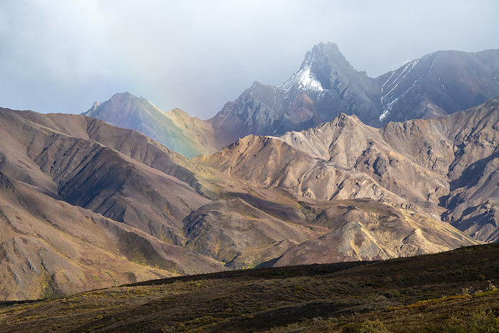 Denali National Park, U.S.A. Brilliant rainbow and a cloudy sky with rugged mountain peaks near Sable Pass  Denali National Park and Preserve, Interior Alaska, Alaska, United States of America, by Kenneth Whitten   Design Pics
