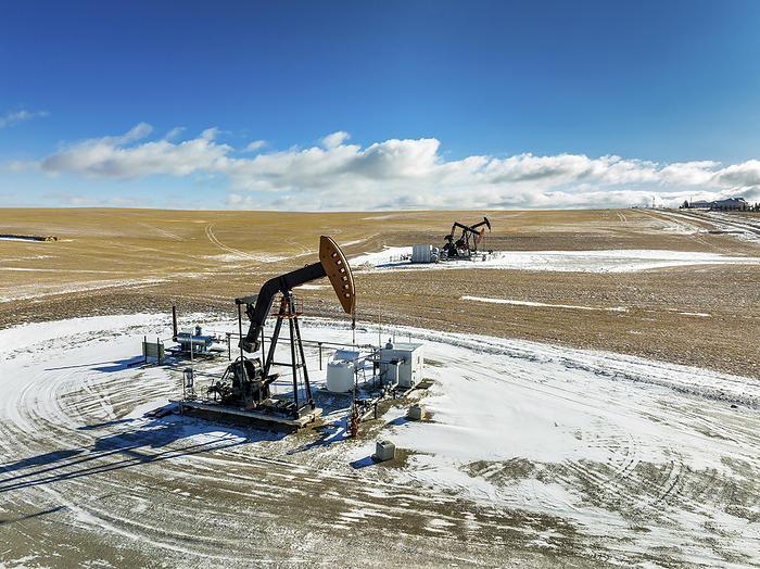 Canada Aerial view of pumpjacks in a snow covered field with dramatic clouds in a blue sky with clouds, West of Airdrie  Alberta, Canada, by Michael Interisano   Design Pics
