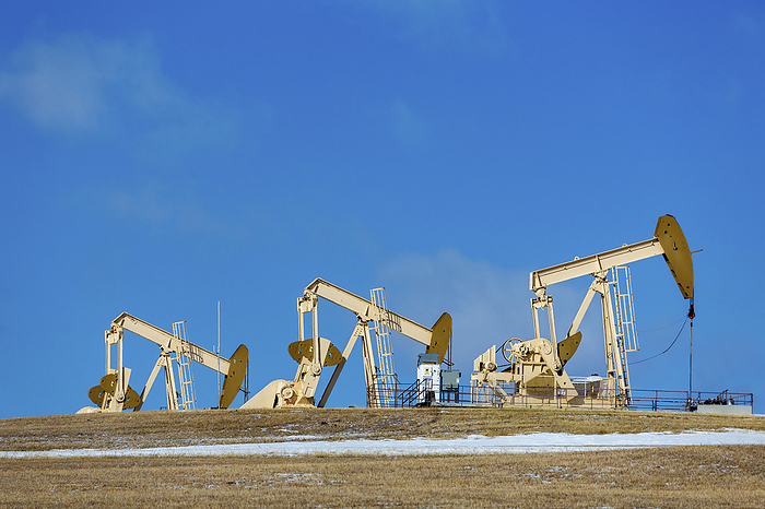 Canada Pumpjacks in a field against a blue sky and a trace of snow, West of Airdrie  Alberta, Canada, by Michael Interisano   Design Pics