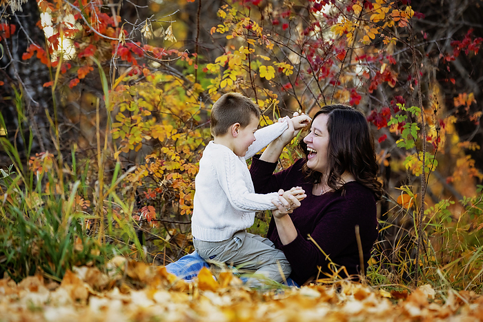 A mother spending quality time and playing with her young son outdoors in a city park during the fall season; Edmonton, Alberta, Canada, by LJM Photo / Design Pics