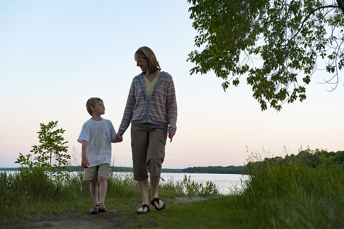 Mother and young son walk along the shores of a lake at dusk, Leech Lake in Minnesota, USA; Walker, Minnesota, United States of America, by Joel Sartore Photography / Design Pics