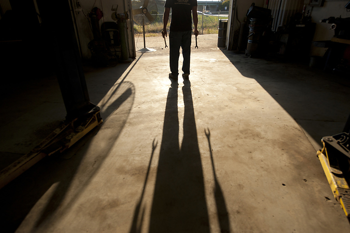 Shadow of a mechanic stretches across the ground of his auto shop; Lincoln, Nebraska, United States of America, by Joel Sartore Photography / Design Pics