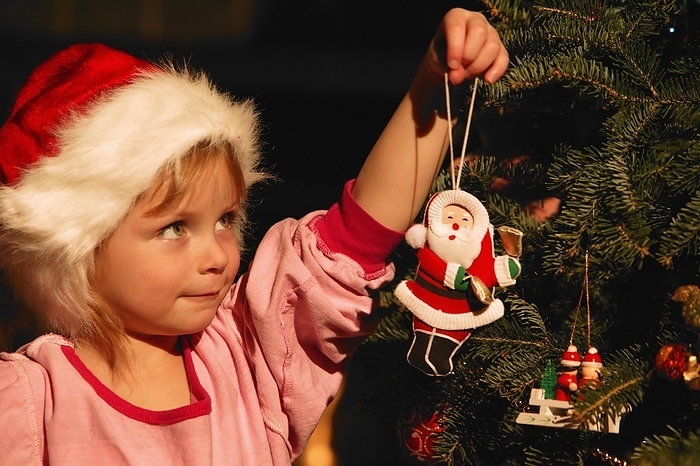 Girl Hanging Ornament On Christmas Tree, by Carson Ganci / Design Pics