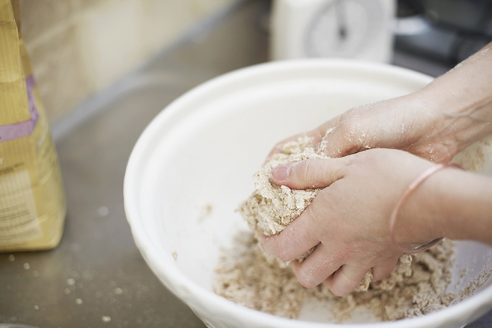 Woman shaping dough in kitchen