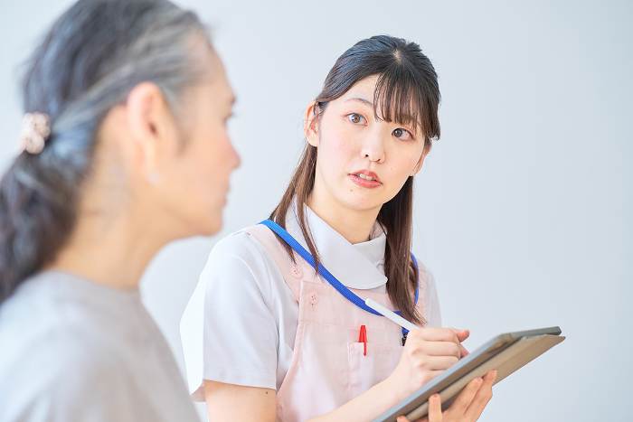 Senior woman conversing with a young Japanese woman in an apron (People)