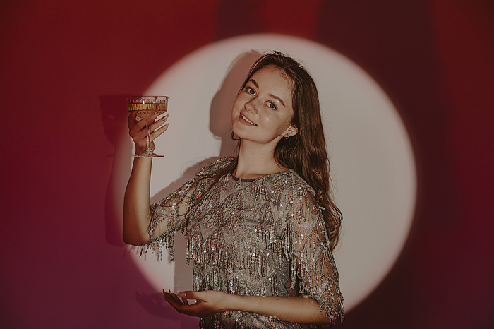 Young woman raising toast against red background