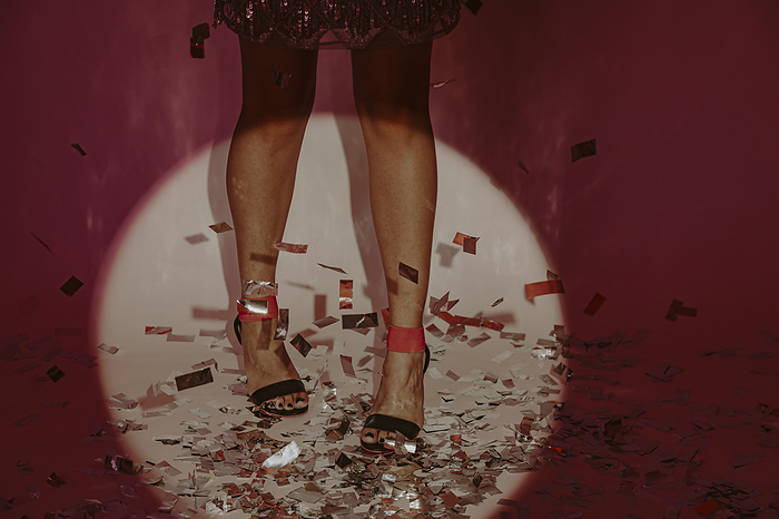 Woman standing on confetti against red background