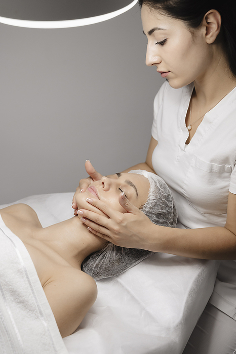 Beautician massaging woman's face with hands