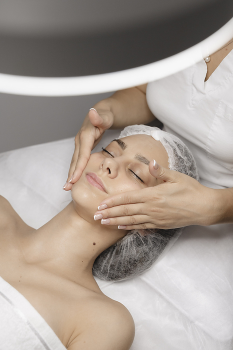Beautician giving facial massage to woman with hands