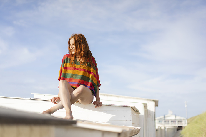 Smiling woman sitting on top of beach hut