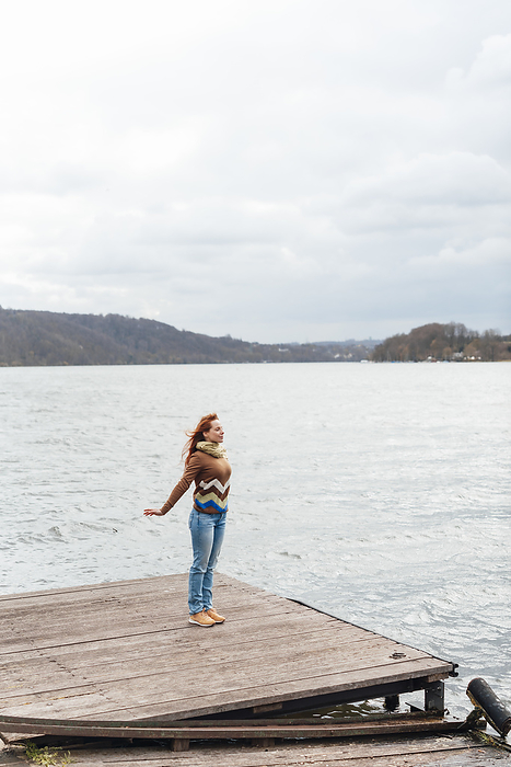Carefree woman standing on pier by lake