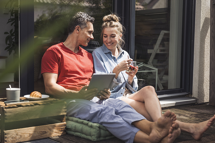 Couple relaxing on balcony with digital tablet