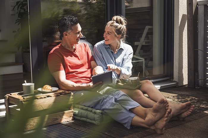 Couple relaxing on balcony with digital tablet
