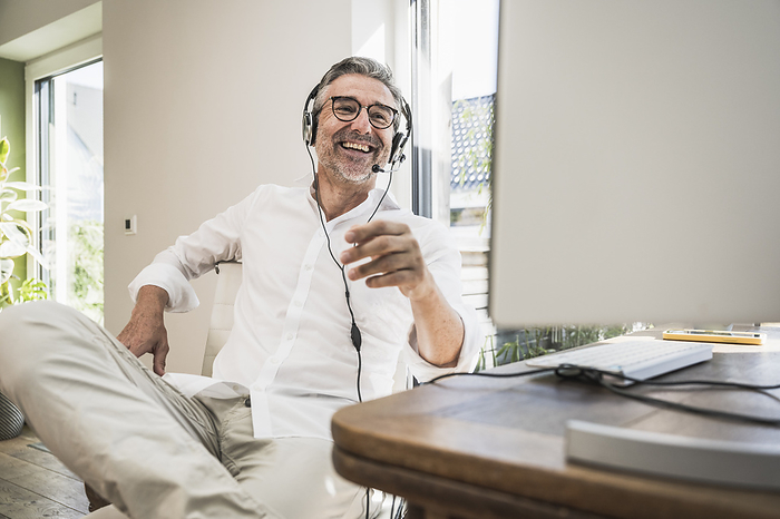 Mature sales representative talking over headset at home office