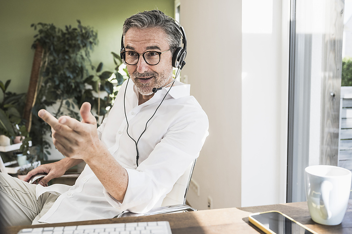 Sales representative gesturing and talking over headset at home office