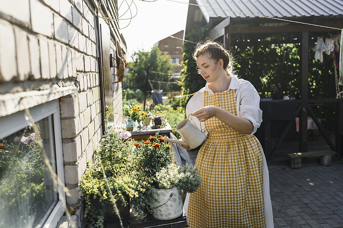 Woman watering plants in garden on sunny day
