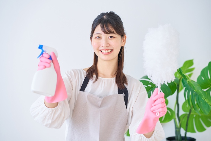 Young Japanese woman in apron holding cleaning tools (People)